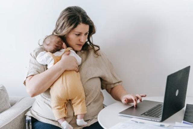 woman holding a baby at a laptop
